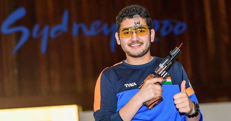 Anish Bhanwala holding his pistol and showing a thumbs up sign