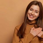 Cheerful young woman with hands over her heart in gratitude