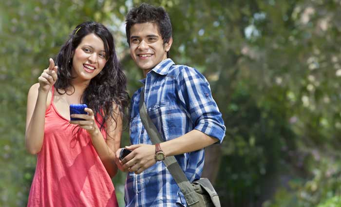 Male and female college friends looking up from cell phones and smiling
