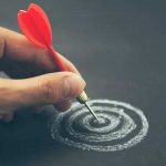 Hand placing a dart onto a hand drawn target