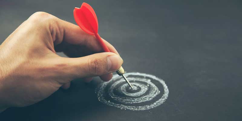 Hand placing a dart onto a hand drawn target