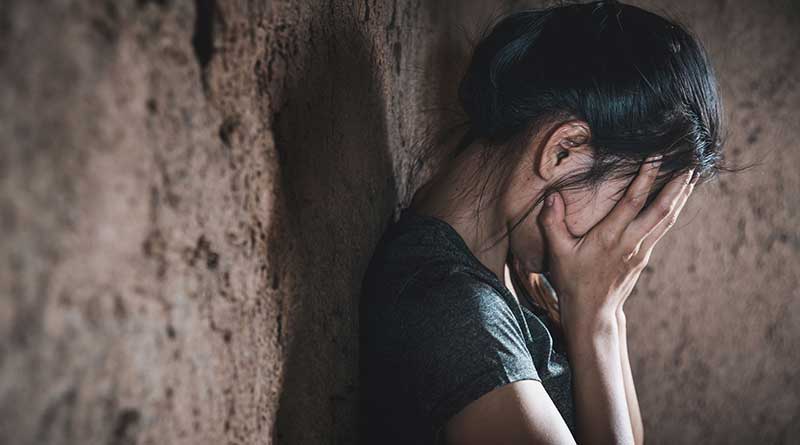 Depressed girl leaning against a wall and covering her face