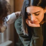 A young woman being comforted by a friend