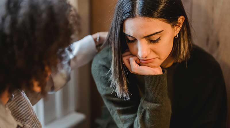 A young woman being comforted by a friend