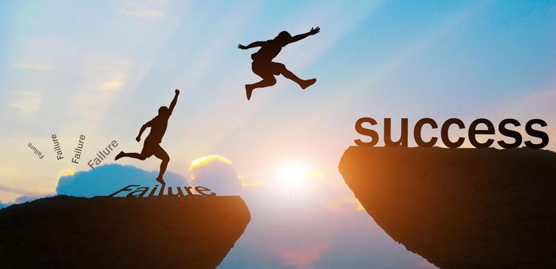 Man jumping from cliff with failure on it to cliff with success on it