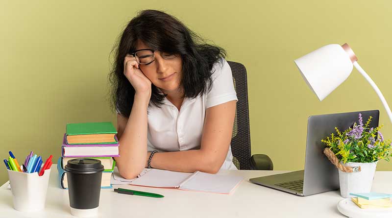 Tired female student sleeping at her desk