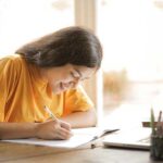 Female student smiling while writing in a book