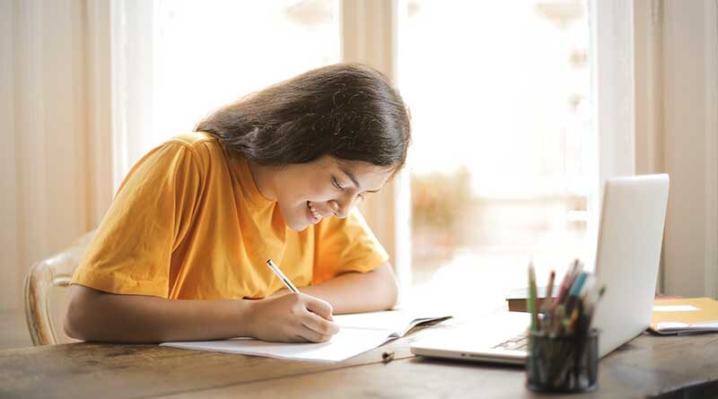 Female student smiling while writing in a book