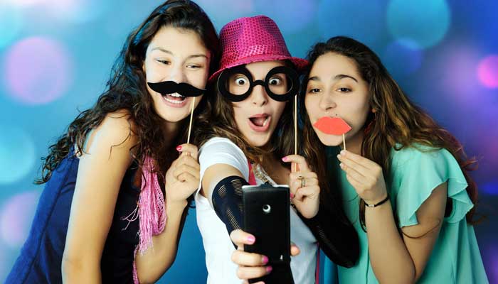 Girls using props to make funny faces to take a selfie
