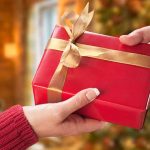 Christmas gift box being passed from one hand to another