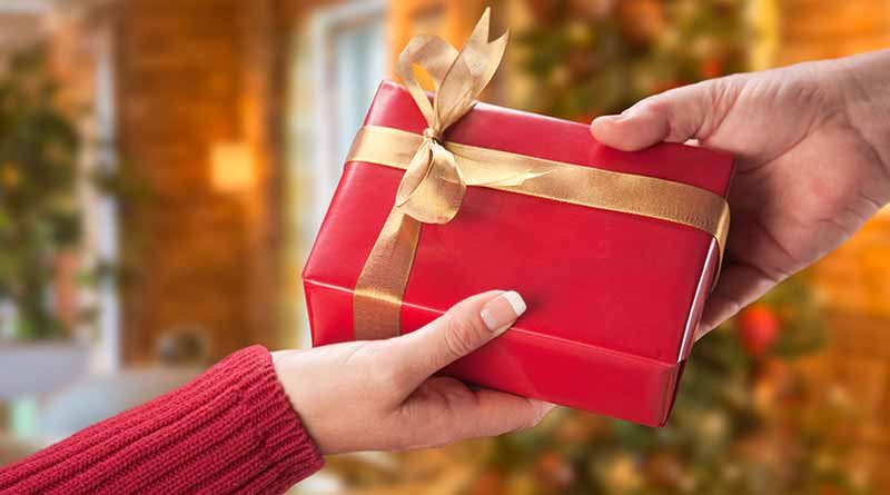 Christmas gift box being passed from one hand to another