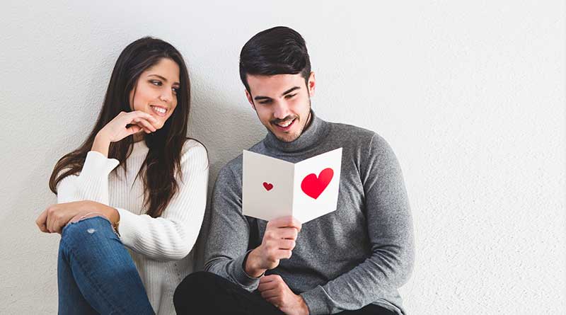 Girl smiling at a boy holding a Valentine's Day card.