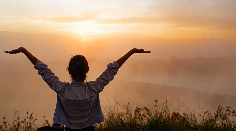 Girl raising her hands to the sunset