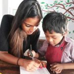 Girl teaching young child as part of community service
