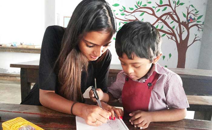 Girl teaching young child as part of community service