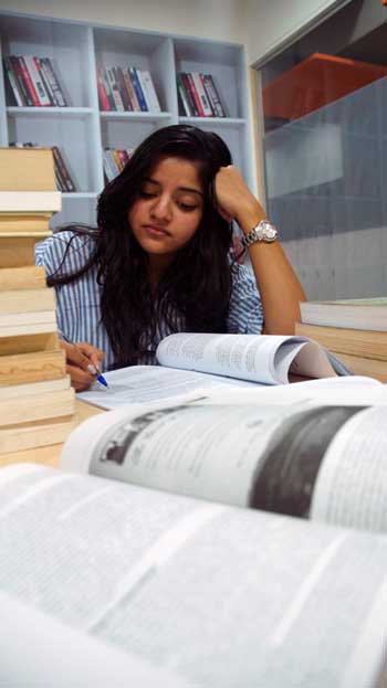 Girl studying for exams with open books in front of her