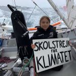 Greta Thunberg holds up a sign on board the Malizia II