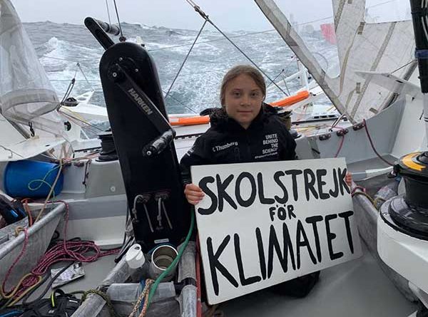 Greta Thunberg holds up a sign on board the Malizia II