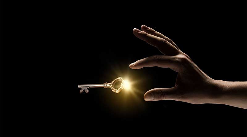 Hand reaching out for glowing golden key