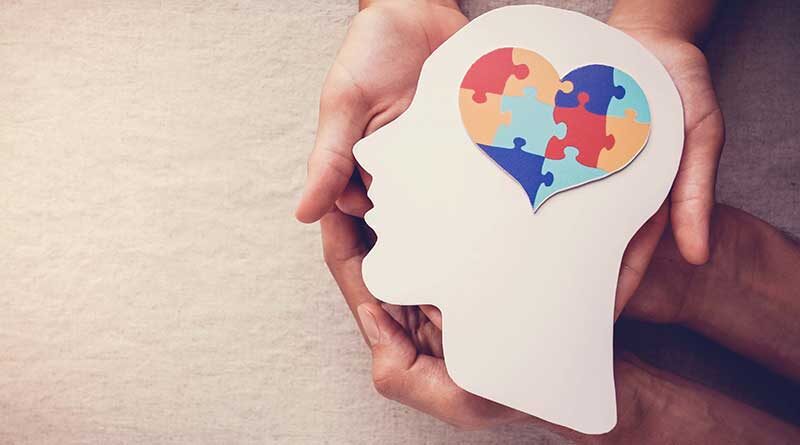 Hand holding a head silhouette with heart jigsaw puzzle