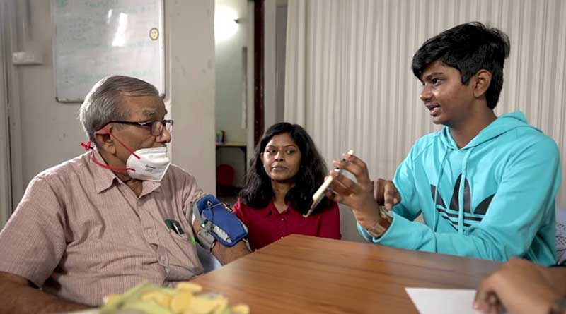 Hemesh Chadalavada, inventor of the Alpha Monitor, demonstrating the device and app to an elderly man