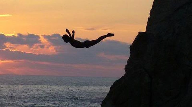 Silhouette of a man diving off a cliff