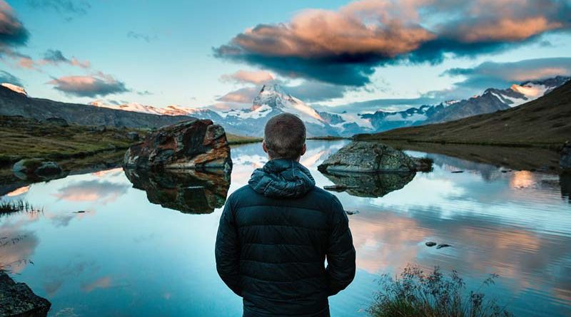Man looking out over a calm lake