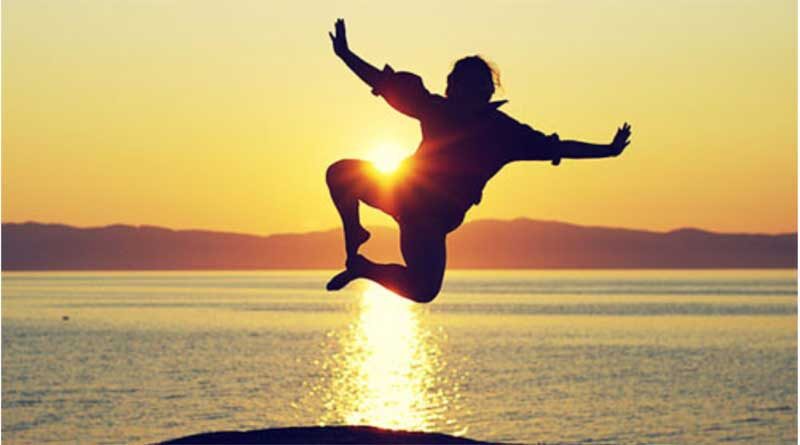 Man clicking his heels and jumping at sunset
