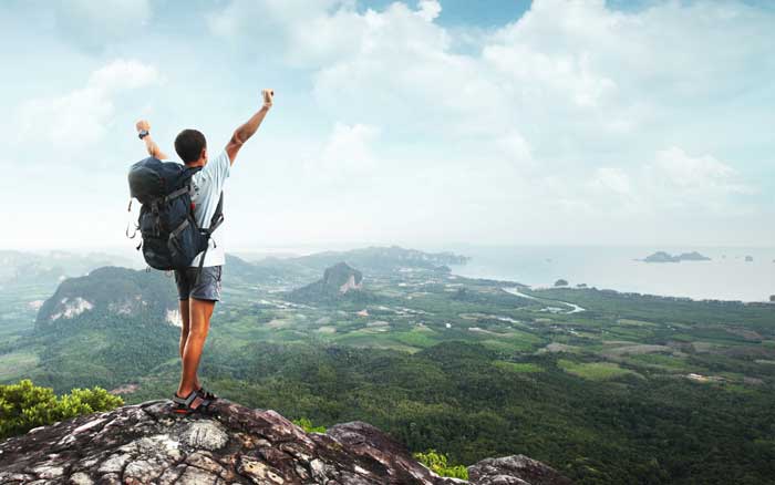 Man standing victoriously on top of a mountain