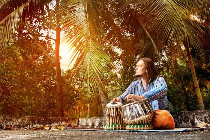 Man playing traditional Indian tabla at sunset