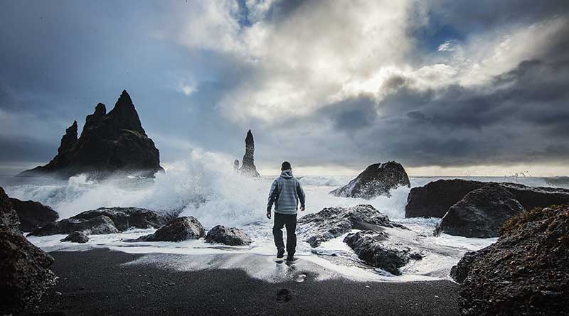 Man walking on seashore in stormy weather