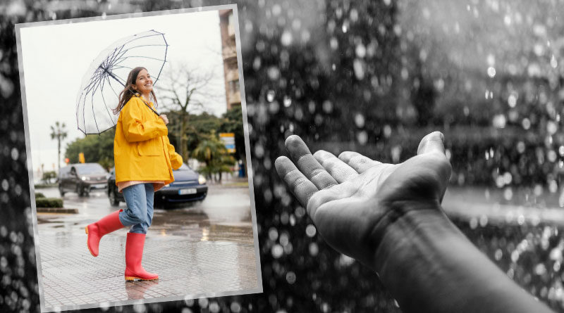 Woman in yellow raincoat with umbrella smiling in the rain