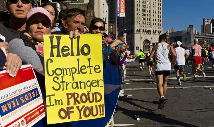 Crowed of people holding up a sign that reads: "Hello complete stranger, I'm proud of you!" at the New York Marathon
