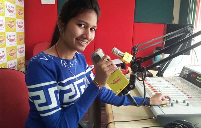Female radio jockey with headphones and console