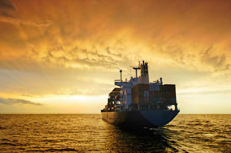 Cargo ship sailing at sunset