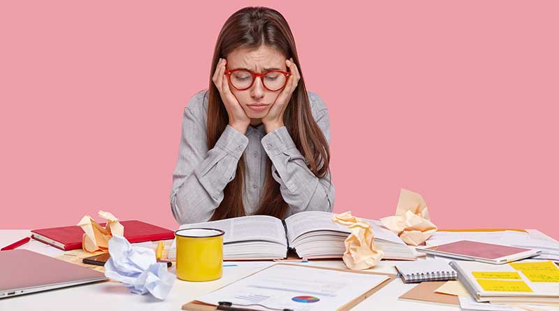 Stressed out female student looking down at her books