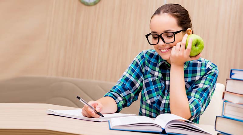 Student holding an apple while studying