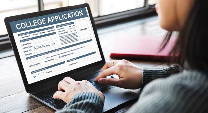 Student typing out a college application on laptop
