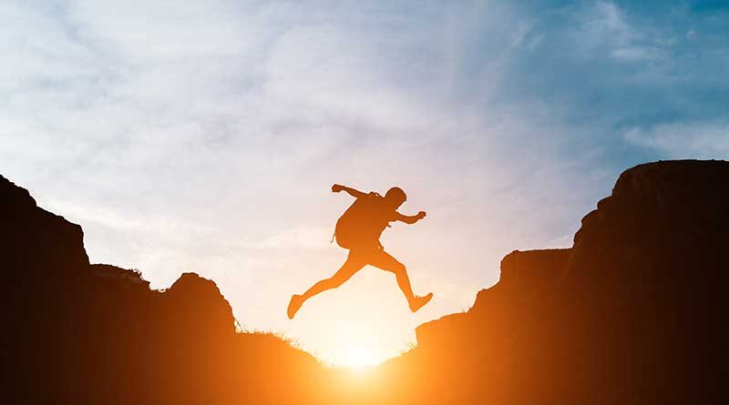 Student jumping over gap in mountain