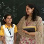 Teacher talking to two students in a classroom