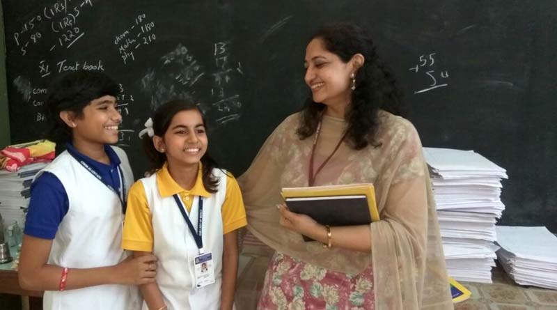 Teacher talking to two students in a classroom