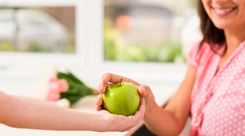 Student handing an apple to the teacher