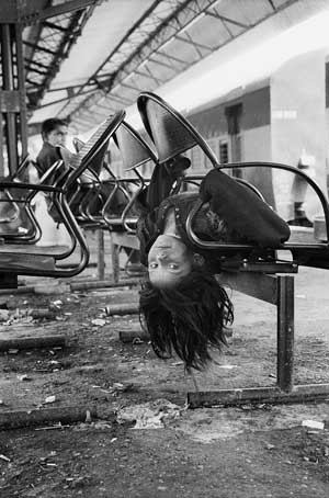Street child playing on railway station bench