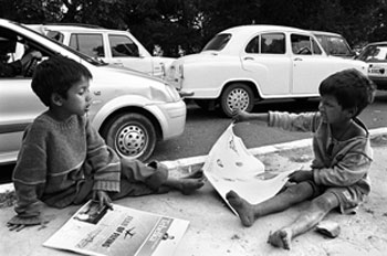 Two street children reading the newspapers on the footpath
