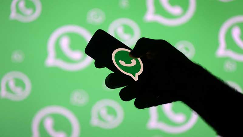 Hand holding phone with WhatsApp symbol on it