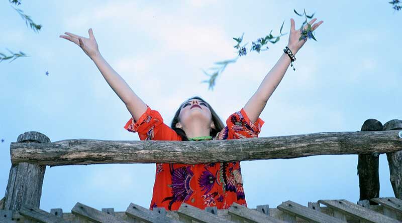 Young woman with outstretched arms throwing flowers in the air