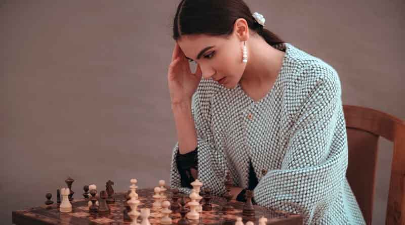 Woman thinking while playing chess