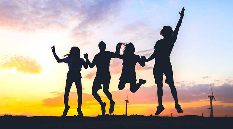 Silhouette of young friends holding hands and jumping