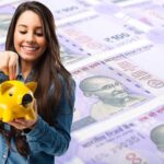 Young girl putting money into a piggy bank
