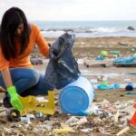 Young woman picking up plastic on a beach